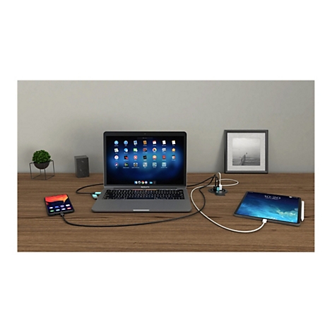 Ordinateur portable, smartphone et tablette connectÃ©s avec une station d'accueil sur un bureau en bois. En arriÃ¨re-plan, une photo et une plante.