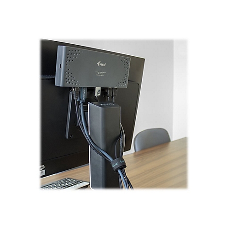 Adaptateur gris fixÃ© Ã  un moniteur, cÃ¢bles regroupÃ©s. Clavier et chaise visibles sur la table.