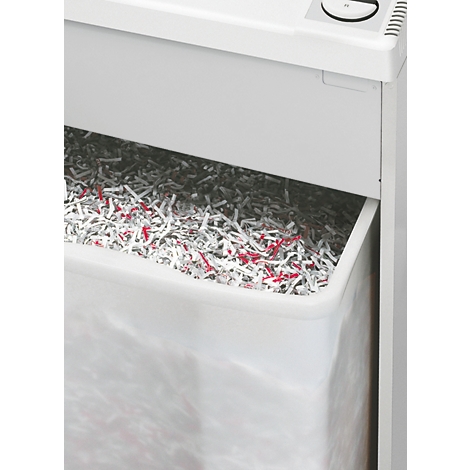 Nahaufnahme eines Aktenvernichters mit gefülltem Auffangbehälter. Papierfetzen in Grau und Rot.
