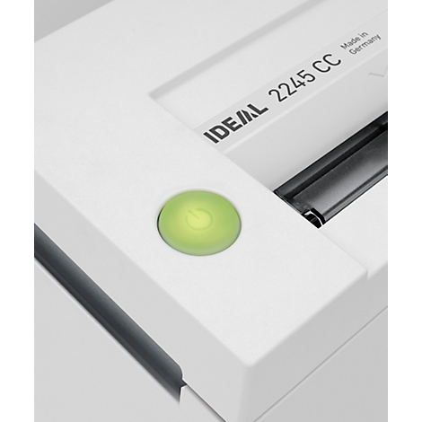 Close-up of a white paper shredder with a green power button.