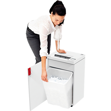 A woman empties a white shredder; paper is spilling from the container.