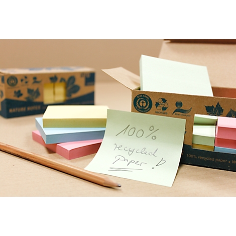 Post-it notes made from 100% recycled paper and a pencil, with more boxes of blocks in the background.