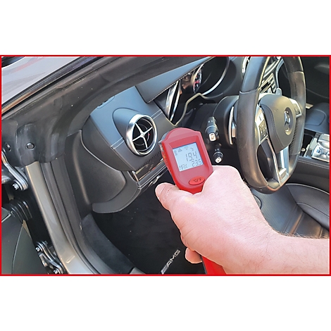 Ein rotes Thermometer zeigt die Temperatur im Armaturenbrett eines Autos. Der Fahrer hält das Gerät. Das Fahrzeug hat ein AMG-Logo.