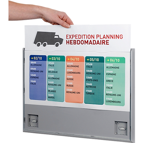 Hand holding a board with a truck symbol and a weekly schedule. Dates, times, and destinations are on colored fields.