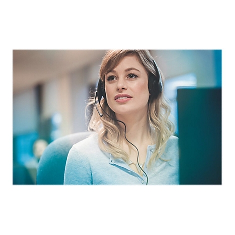 Une femme avec un casque souriant pendant une conversation sur l'ordinateur.