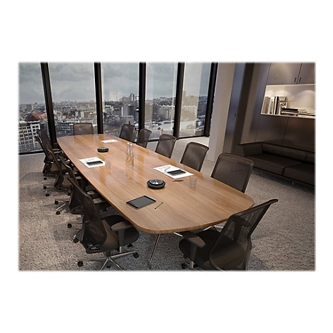Une salle de confÃ©rence avec une table ovale en bois, entourÃ©e de chaises de bureau. De grandes fenÃªtres offrent une vue sur une ville.