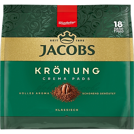 Grüne Kaffeepad-Verpackung von Jacobs Krönung mit goldener Krone, Logo und Kaffeebohne vor gemahlenem Kaffee.