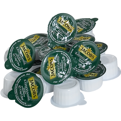 Haufen von Jacobs Kaffeesahne-Portionen, grüne Deckel mit weißem Text. Einige weiße Becher sind ebenfalls sichtbar.