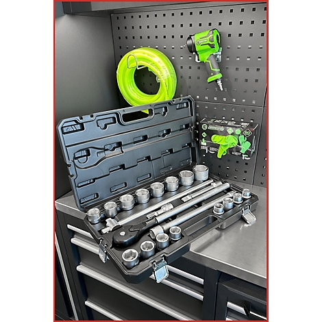 Une boîte à outils avec un jeu de douilles sur un établi devant un panneau perforé avec des outils pneumatiques verts.