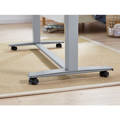 Gros plan des roulettes sous un bureau gris sur un tapis beige.
