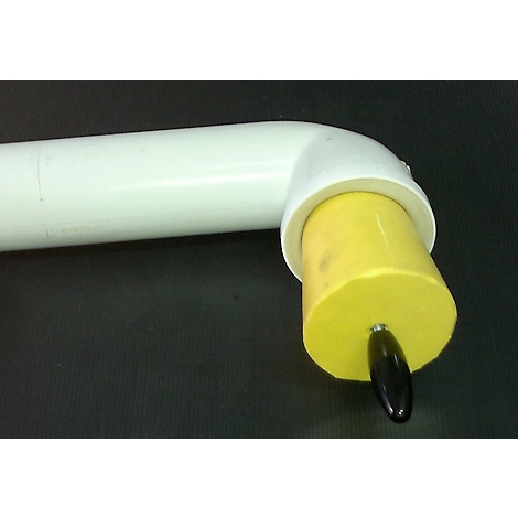 Gros plan d'un cylindre jaune avec une poignée noire fixée à un raccord coudé blanc en tuyau PVC.