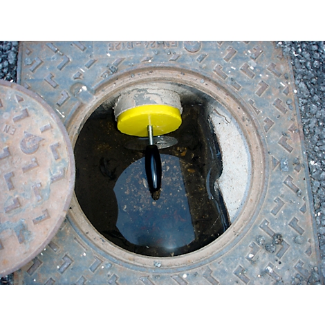 Trou d'homme ouvert avec un appareil de mesure jaune dans l'eau. Un autre couvercle à côté.