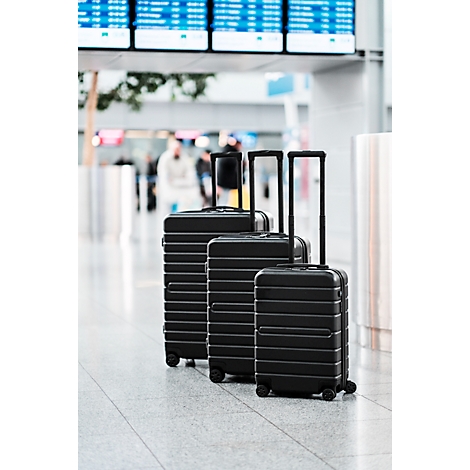 Trois valises noires avec des poignées déployées sont alignées à l'aéroport.