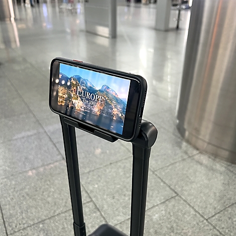 Smartphone dans un support sur une poignée de valise. Sur l'écran : publicité pour l'Europe.