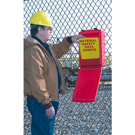 Mann im braunen Mantel mit gelbem Helm und roter Box an einem Maschendrahtzaun. Aufschrift auf der Box: Materialsicherheitsdatenblätter.