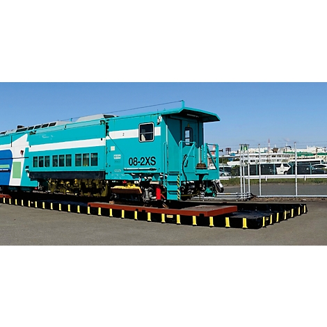 Turquoise trein staat op een zwart spoor. Blauwe lucht op de achtergrond.