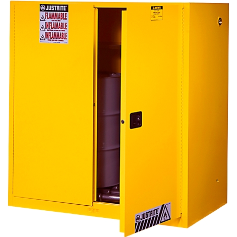 Yellow open steel safety cabinet, a barrel stands inside. Label: "JUSTIRITE FLAMMABLE INFLAMMABLE".