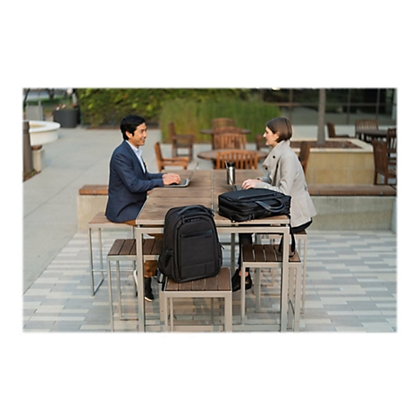 Zwei Personen sitzen an einem Tisch im Freien. Ein Mann tippt an einem Laptop, eine Frau sitzt ihm gegenÃ¼ber.