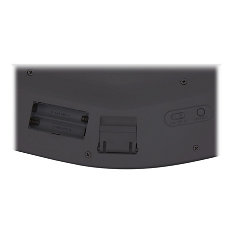 Gros plan sur l'arrière d'un clavier gris. Compartiments de batterie ouverts, étiquetés avec "AAA 1.5V", interrupteurs pour 2.4G OFF BT et Connect.