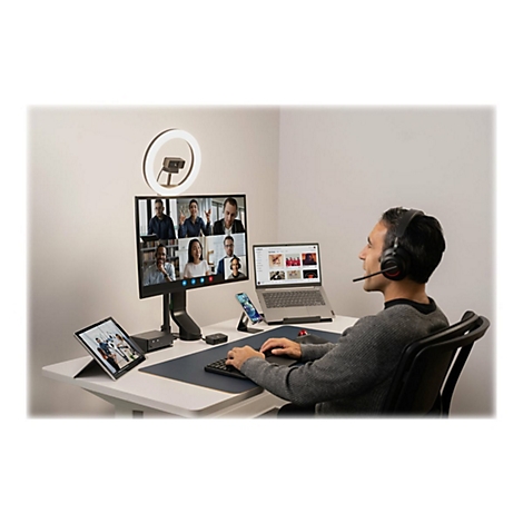 Un homme avec un casque participe Ã  une vidÃ©oconfÃ©rence. Sur la table : ordinateur portable, tablette, smartphone, anneau lumineux, moniteur.