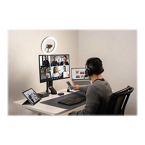 Personne en appel vidÃ©o avec PC, tablette et accessoires. Anneau lumineux en arriÃ¨re-plan.