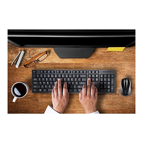 Draufsicht auf einen Schreibtisch mit Computer, Tastatur, Maus, Kaffeetasse und HÃ¤nden, die tippen.