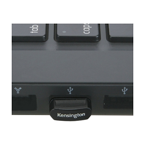 Nahaufnahme eines schwarzen USB-Empfängers mit dem Schriftzug "Kensington" auf der Unterseite. Er steckt in einem Laptop.