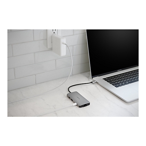 Un ordinateur portable est connectÃ© Ã  l'alimentation et Ã  d'autres appareils via un hub gris. Le hub repose sur une surface marbrÃ©e. Une prise de courant est en arriÃ¨re-plan.