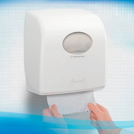 Ein weisser Papierspender wird von einer Person bedient. Auf dem Spender steht "Kimberly Clark".