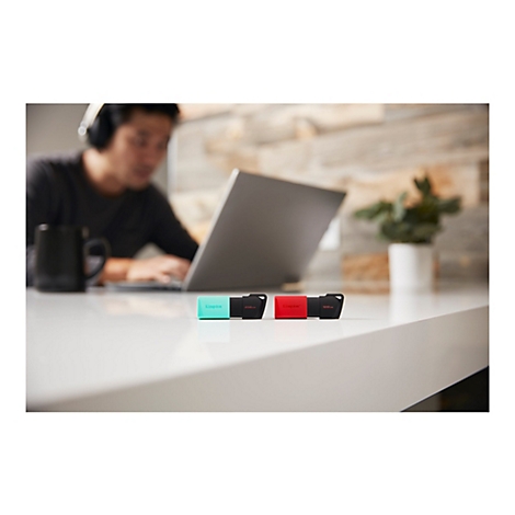 ClÃ©s USB colorÃ©es sur un bureau. Une personne portant un casque travaille sur un ordinateur portable.