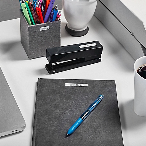 Bureau rangé avec porte-stylo étiqueté, agrafeuse, carnet et une tasse de café.