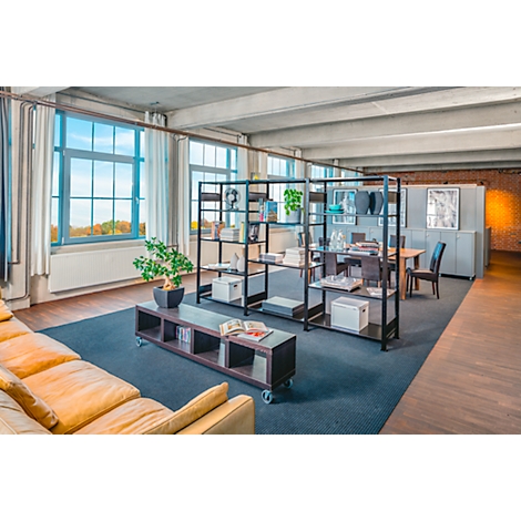 Salon avec mobilier moderne: canapé, étagère, table, fenêtres et vue sur la verdure. Ambiance soignée.