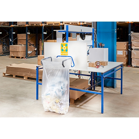 Poste de travail dans un entrepôt. Un sac en plastique transparent est suspendu à une table. Il y a d'autres matériaux sur la table.