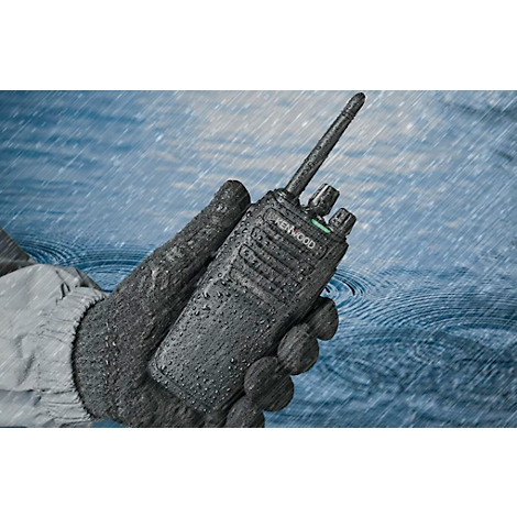 Une radio portative dans un environnement humide, tenue par une main gantée. Des gouttes tombent sur l'appareil.