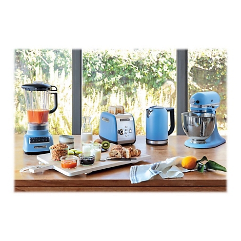 Blaues KitchenAid-Frühstücksset mit Mixer, Toaster, Wasserkocher und Küchenmaschine auf einem Holztisch.