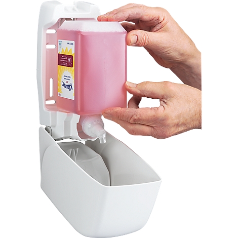 Hands holding a pink soap refill over a white soap dispenser.