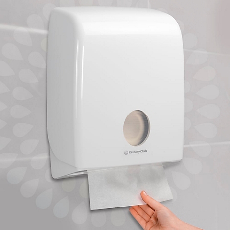 Dispensador de toallas de papel blanco Kimberly-Clark. Una mano saca una toalla de papel.