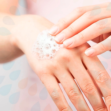 Nahaufnahme einer Hand, die mit Seifenschaum bedeckt ist. Eine andere Hand reibt sanft ein.