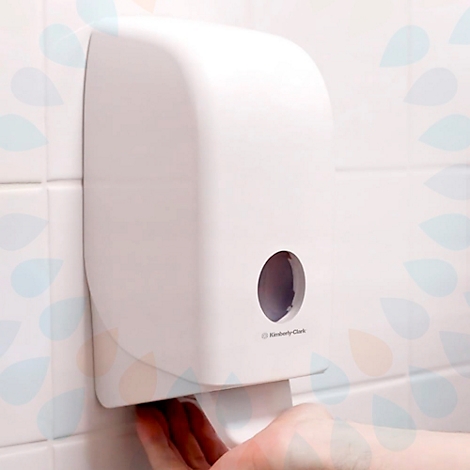 Een witte papieren handdoekdispenser wordt gebruikt door een hand die een papieren handdoek pakt. Op de dispenser staat "Kimberly-Clark".