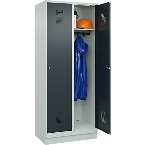 Ein Stahlschrank mit zwei Fächern, eines geöffnet. Im offenen Fach: Helm, Jacke und Flasche.