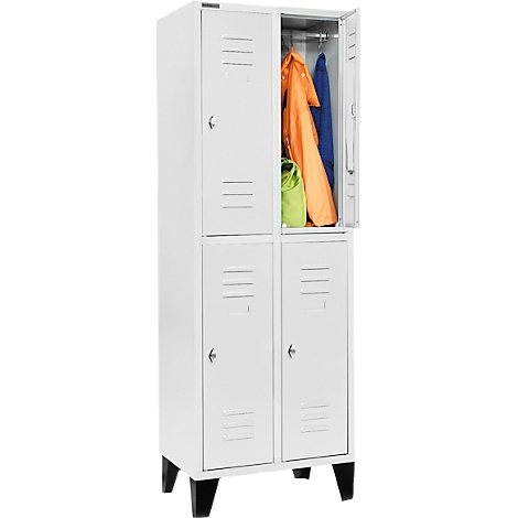Ein weißer Schrank, mit 4 Fächern. Oben rechts ist die Tür geöffnet, mit Kleidung und einer Tasche. Schwarze Füße.