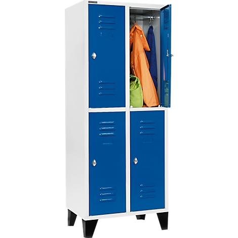 Weißer Schrank mit vier blauen Türen. Eine Tür ist geöffnet und zeigt Kleidung, eine grüne Tasche.