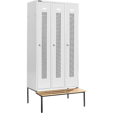 Dreifach-Spindschrank in Weiß mit Lochmuster, darunter eine Bank aus Holz und schwarzen Metallbeinen.