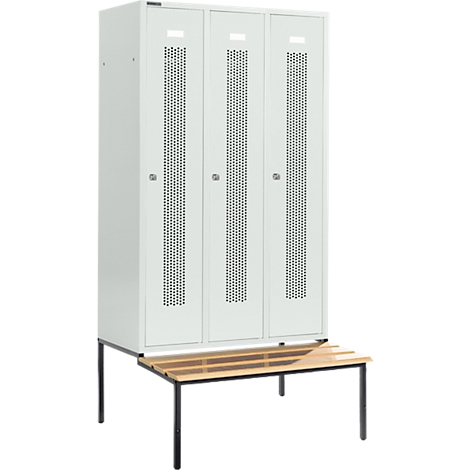 Schrank mit drei Türen und Lochmuster. Darunter eine Holzbank mit schwarzen Beinen.