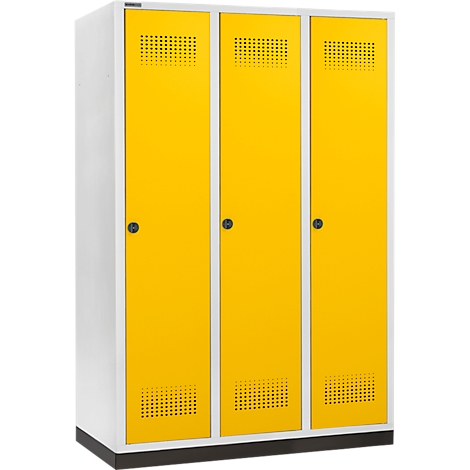 Schrank in Weiß und Gelb mit drei Türen, jeweils mit einem Griff. Der obere Bereich der Türen ist gelocht.