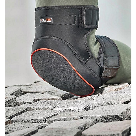 Genouillère noire avec bordure rouge, sur sol en pierre, jambe dans un pantalon vert olive.