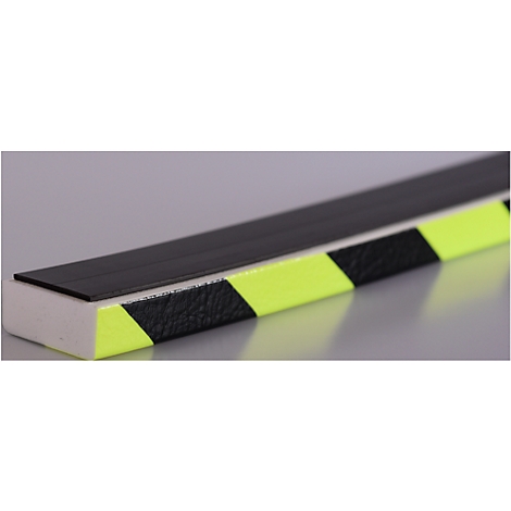 Primer plano de una tira rectangular negra, que descansa sobre una superficie blanca. La tira tiene rayas amarillas y negras.
