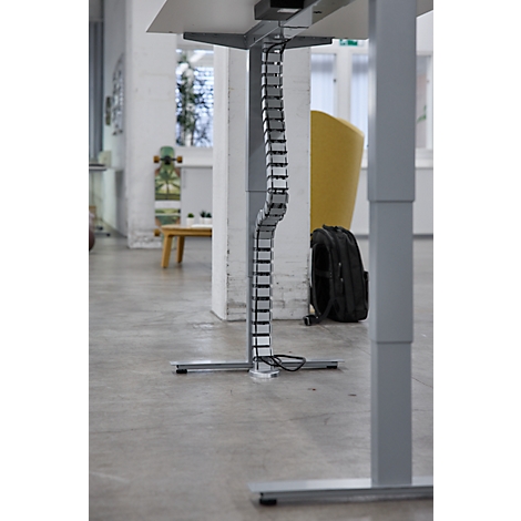 Detailaufnahme einer Kabelführung unter einem höhenverstellbaren Schreibtisch.Graue Kabel werden elegant in einer Schiene geführt.