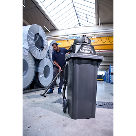 Ein Arbeiter reinigt mit dem Industriestaubsauger Marutec Mammut eine Lagerhalle mit Metallrollen.