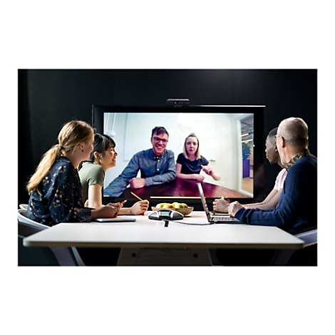 Gruppe von Kollegen in Videokonferenz. Auf dem Bildschirm: zwei Personen lachen. Auf dem Tisch: Obst, Laptop, Telefon, Notizbuch.